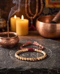 Tibetan Copper Shield Bracelet on an altar with incense and candles - Red