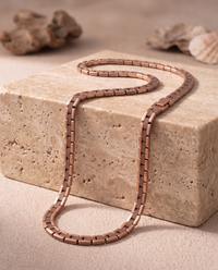 Copper Shield Magnetic Necklace draped over a stone edge
