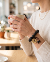 Woman wearing the Buddha Mala Bracelet while holding a coffee cup