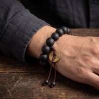 The Buddha Mala Bracelet worn on the wrist with the lucky coin hanging at the front
